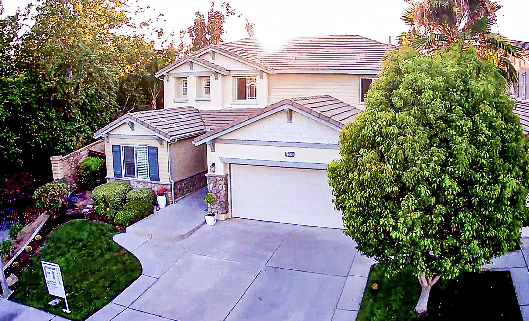 Aerial view of the home's facade, driveway and mature landscaping